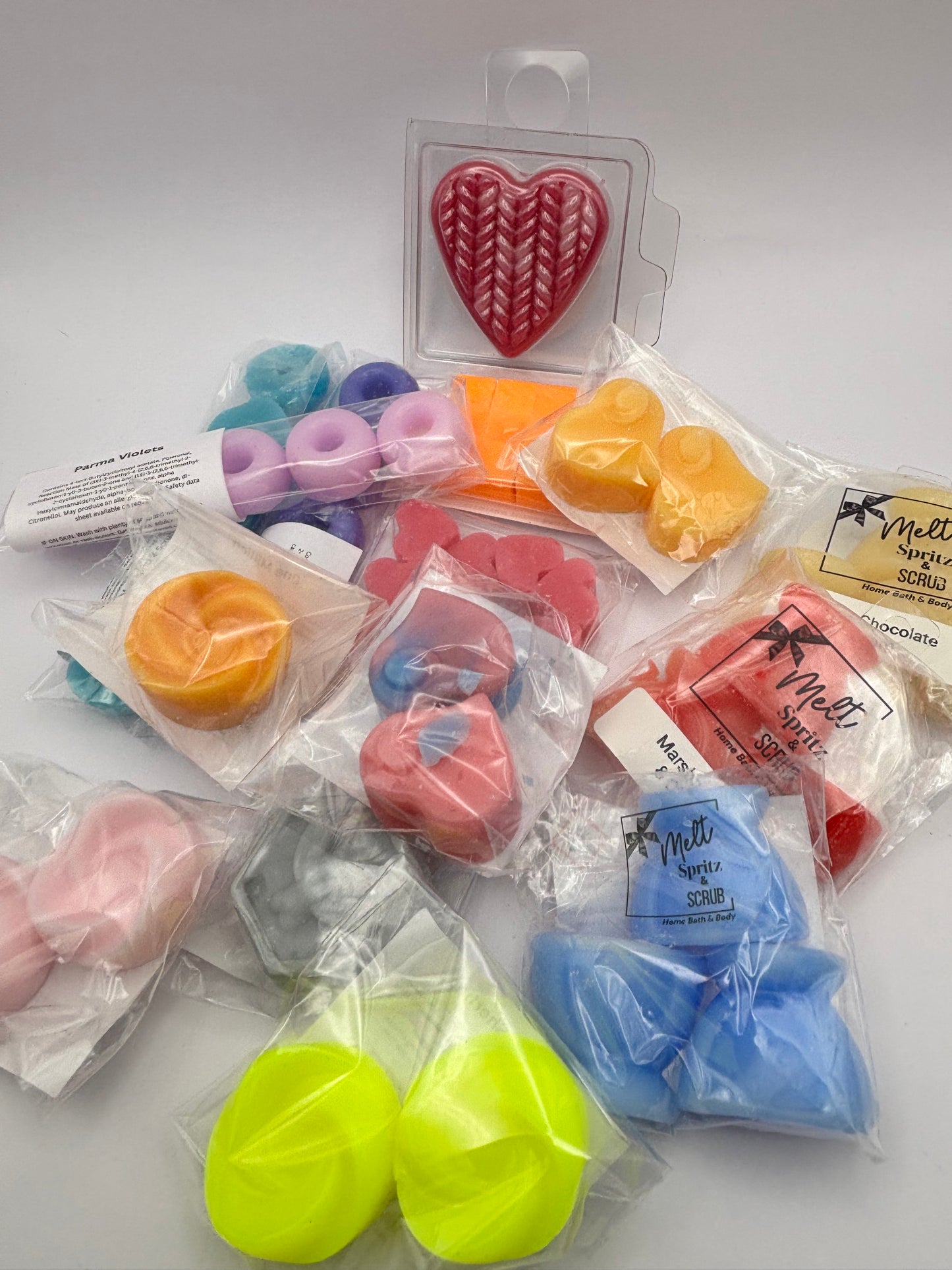 Colorful shaped wax melts in clear packaging on a white background